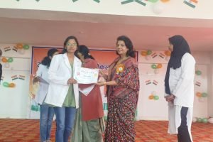 A woman holds a certificate while surrounded by a group of smiling people celebrating her achievement.